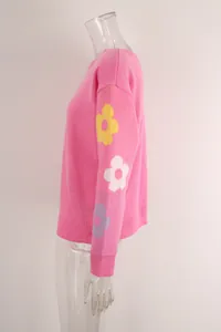 Detailed side view of pink knit sweater featuring colorful floral patterns on sleeves