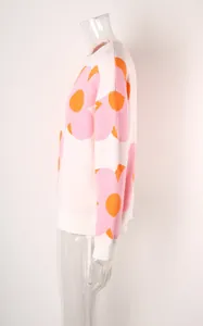 Side view of women's white knit sweater featuring large pink and orange floral prints