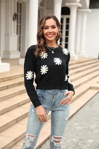 Stylish black knitted sweater featuring white daisy floral patterns and crewneck design.