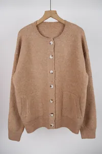 Full front view of a tan knit cardigan with round neck and buttons on a wooden hanger.