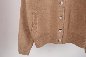 Close-up of a cozy brown knit cardigan featuring marbled buttons and ribbed pocket details.