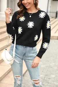 Detail view of women's black crewneck sweater with white daisy floral knit pattern