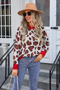 Detailed view of women's leopard print knit sweater featuring red ribbed crew neck and cuffs