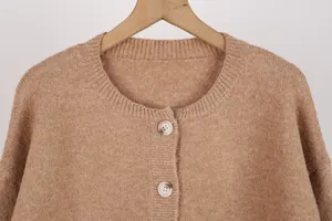 Detail of a brown knitted cardigan featuring a round neckline and white buttons texture