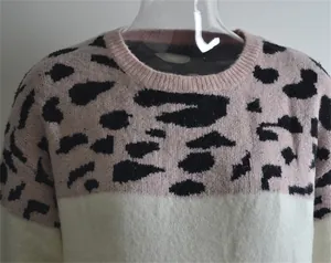 Detail of a pink and white patchwork knit sweater with bold leopard print pattern