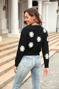 Detailed back view of black knit sweater featuring white daisy floral patterns.