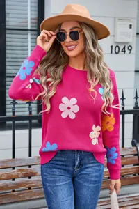 Detailed view of pink knitted sweater with vibrant floral patterns and ribbed collar
