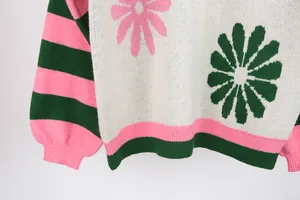 Detailed macro shot of knit sweater featuring pink flower pattern and green striped hem.