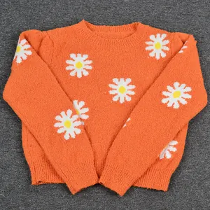 Bright orange short knit sweater featuring white daisy flower patterns and crew neck