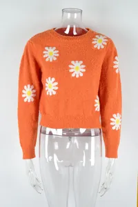 Detailed front view of vibrant orange knit sweater with white daisy patterns on a mannequin.