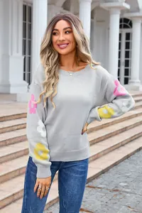 Close-up detail of grey boat neck knitted sweater featuring colorful floral sleeves.
