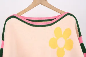 Close-up of pink knitted sweater with yellow flower and striped boat neck detail