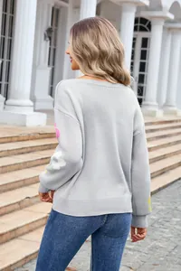 Back view of a light gray knit sweater with floral sleeve details and boat neck.