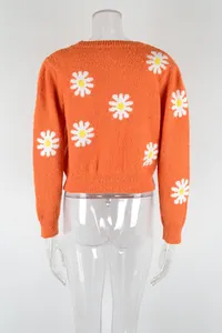 Back view of short orange knit sweater with white daisy floral patterns on a clear mannequin