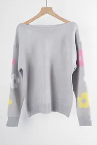 Close-up detail of grey loose knitted sweater with colorful flower sleeve patterns and boat neck
