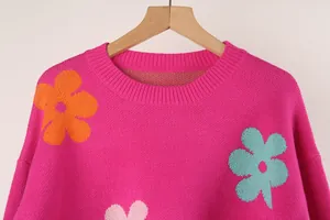 Detail view of a bright pink round neck knit sweater with flower and heart patterns