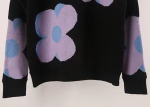 Close-up detail of women's black sweater featuring large purple and blue floral print