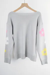 Detailed view of gray boat neck sweater with colorful floral patterns on sleeves.