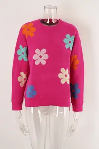 Detail view of pink knitted sweater with vibrant multi-colored floral pattern crew neck