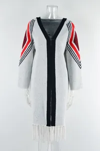 Detail view of long knitted cardigan with red geometric sleeve patterns and white fringe hem.
