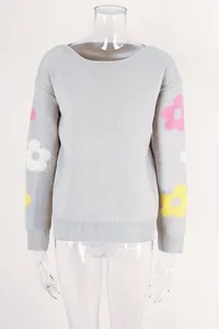 Detail of light grey knit sweater featuring colorful floral patterns on sleeves.