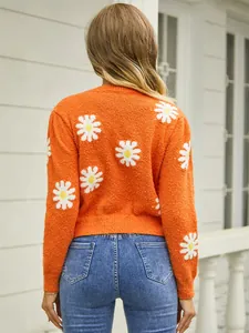 Back view of a vibrant orange knit sweater featuring white daisy floral patterns.