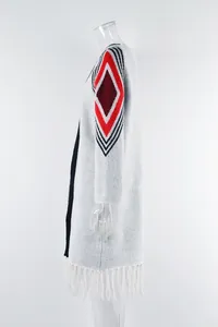 Side view of white long sleeve knit cardigan featuring a red diamond pattern and fringe