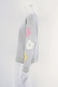 Side view of a grey boat neck sweater featuring colorful flower patterns on the sleeve