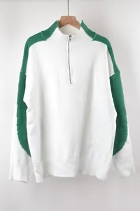 Detail van de witte oversized gebreide trui met groene accenten en kraag met rits