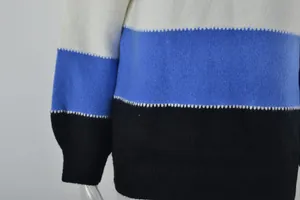 Close-up of women's color-block knit sweater showing blue and black stitching details.