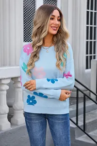Detailed view of colorful floral jacquard patterns on a light blue round neck sweater