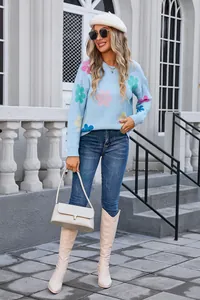 Detail view of light blue round neck sweater with colorful floral patterns and knit texture