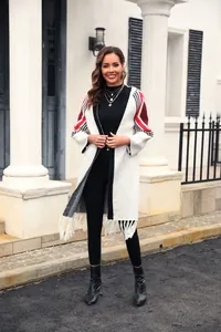 Full body shot of a model wearing a long white knit cardigan with fringe and sleeve patterns
