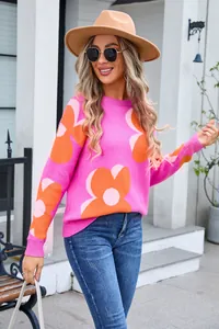 Close-up detail of women's vibrant pink round neck sweater with large orange floral knit pattern