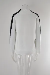 Detail van het achteraanzicht van de witte oversized gebreide trui met zwarte schouderstrepen