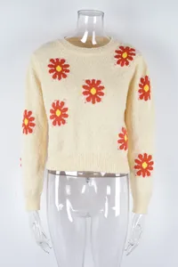 Detailed view of cream knit sweater featuring vibrant orange and yellow daisy patterns.