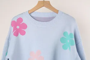Close-up of knit texture and colorful flower patterns on a blue round neck sweater