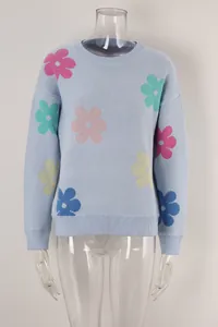 Detailed view of light blue round neck knit sweater with colorful floral patterns