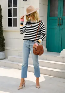 Vue d'une femme portant un pull rayé avec des poignets contrastés et un jean bleu.