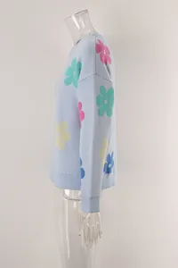 Side detail of light blue knitted sweater with vibrant floral patterns on clear mannequin