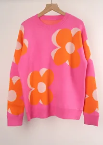 Detail view of pink knit sweater featuring large orange flower prints and round neck