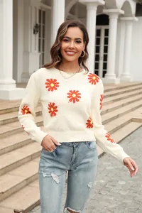 Detailed view of the stylish cream knit sweater featuring bright orange daisy patterns.