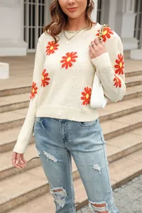 Detail of soft cream knit sweater with vibrant red and yellow daisy floral patterns