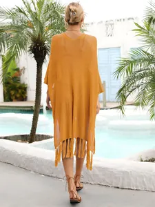 Detailed back view of a mustard yellow crochet knit beach cover-up with fringe tassels