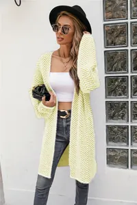 Full view of woman in stylish long yellow chevron knit cardigan with black hat.