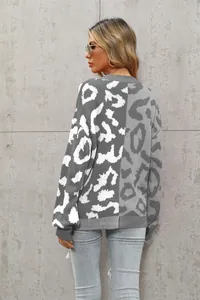 Rückansicht eines grau-weißen Strick-Cardigans mit Leopardenmuster vor einer grauen Wand.