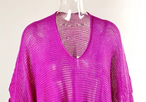 Detail view of the V-neckline and hollow-out crochet mesh on a magenta beach cover-up