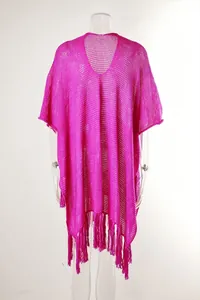 Detail view of a vibrant pink hollow-out knit beach cover-up with decorative tassel hem.