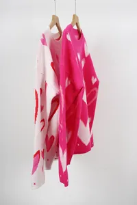 Detail view of soft pink and rose pink oversized sweaters with heart pattern.