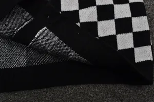 Close-up of black and white checkerboard knit sweater showing fabric texture and hem.